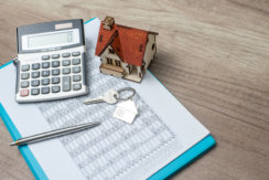Photo of a calculator, expenses and a house
