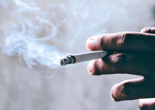 Photo of person holding a lit cigarette